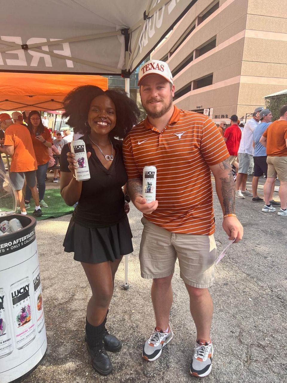 Events — Lucky Energy tailgate activation with brand ambassador and guest in Texas cap holding sample cans