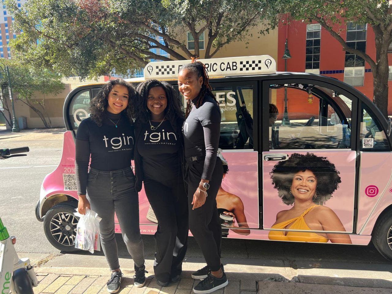 Events — Three tgin brand ambassadors with product sample bags beside a pink Electric Cab promotional shuttle