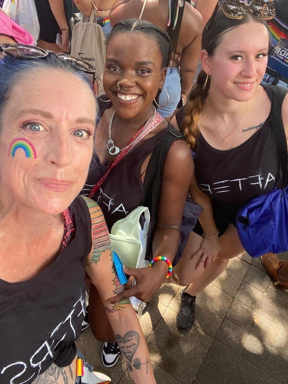 Events — Selfie of three AFTERS brand ambassadors with rainbow face paint in the crowd at a Pride festival