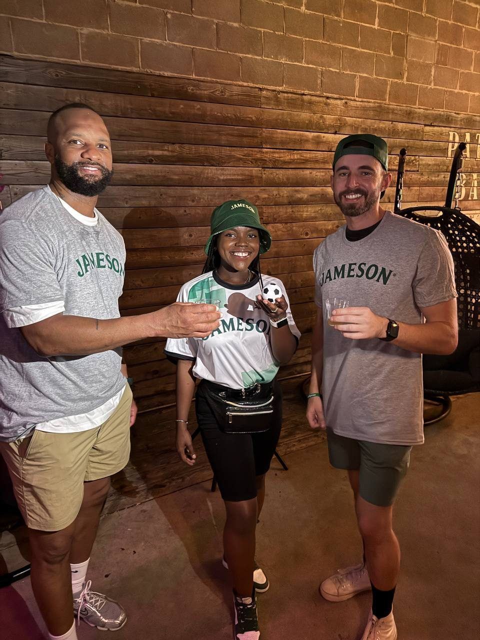 Events — Jameson brand ambassador with mini soccer ball sharing whiskey samples with two guests in Jameson shirts