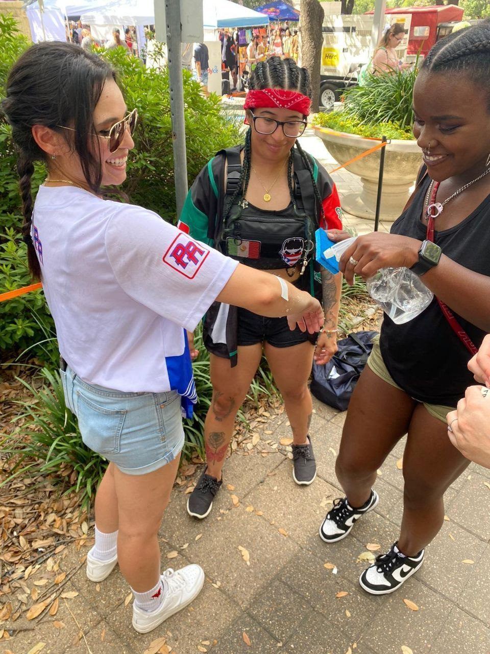 Events — Brand ambassador applying a temporary tattoo to a guest's forearm at a busy outdoor festival