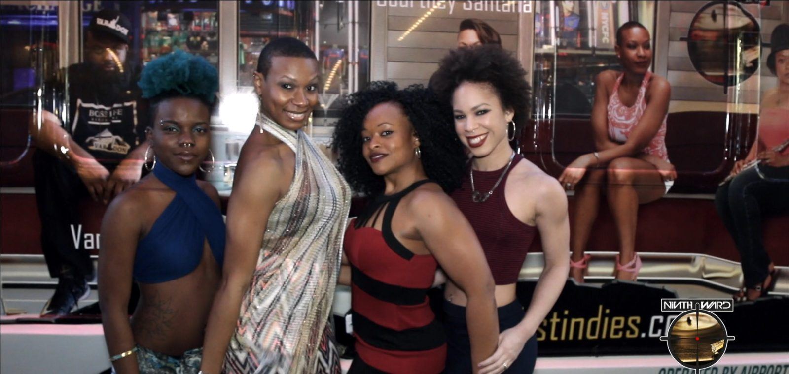 Events — Four brand ambassadors in evening attire posing in front of an open-top tour bus at a nighttime event
