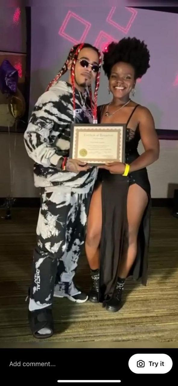 Influencer Work — Two creators posing with a framed certificate at a purple-lit indoor event with balloons