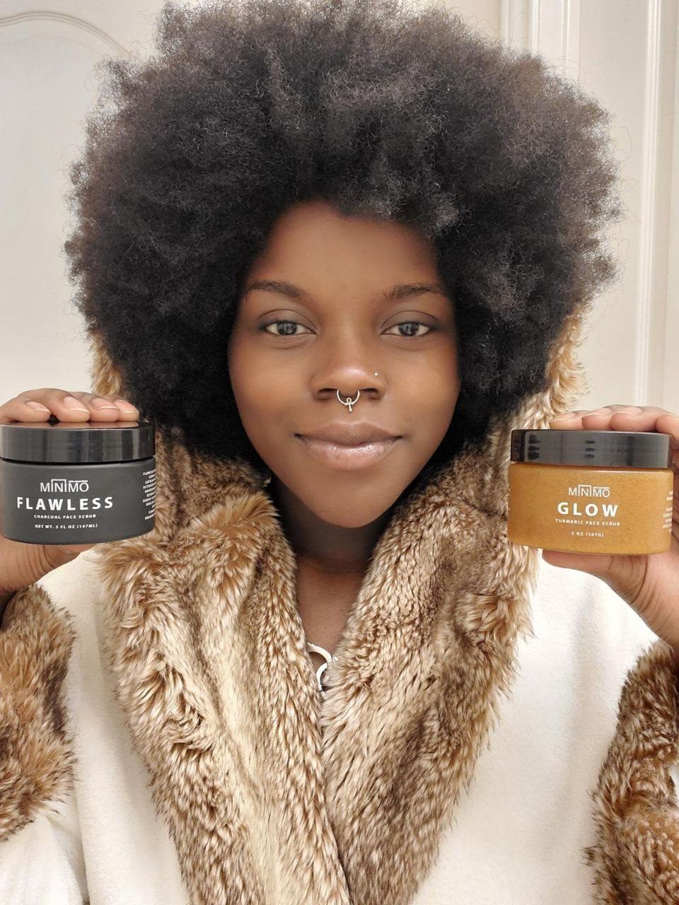Influencer Work — Creator in a fur-trimmed robe holding jars of Minimo Flawless and Glow face scrubs