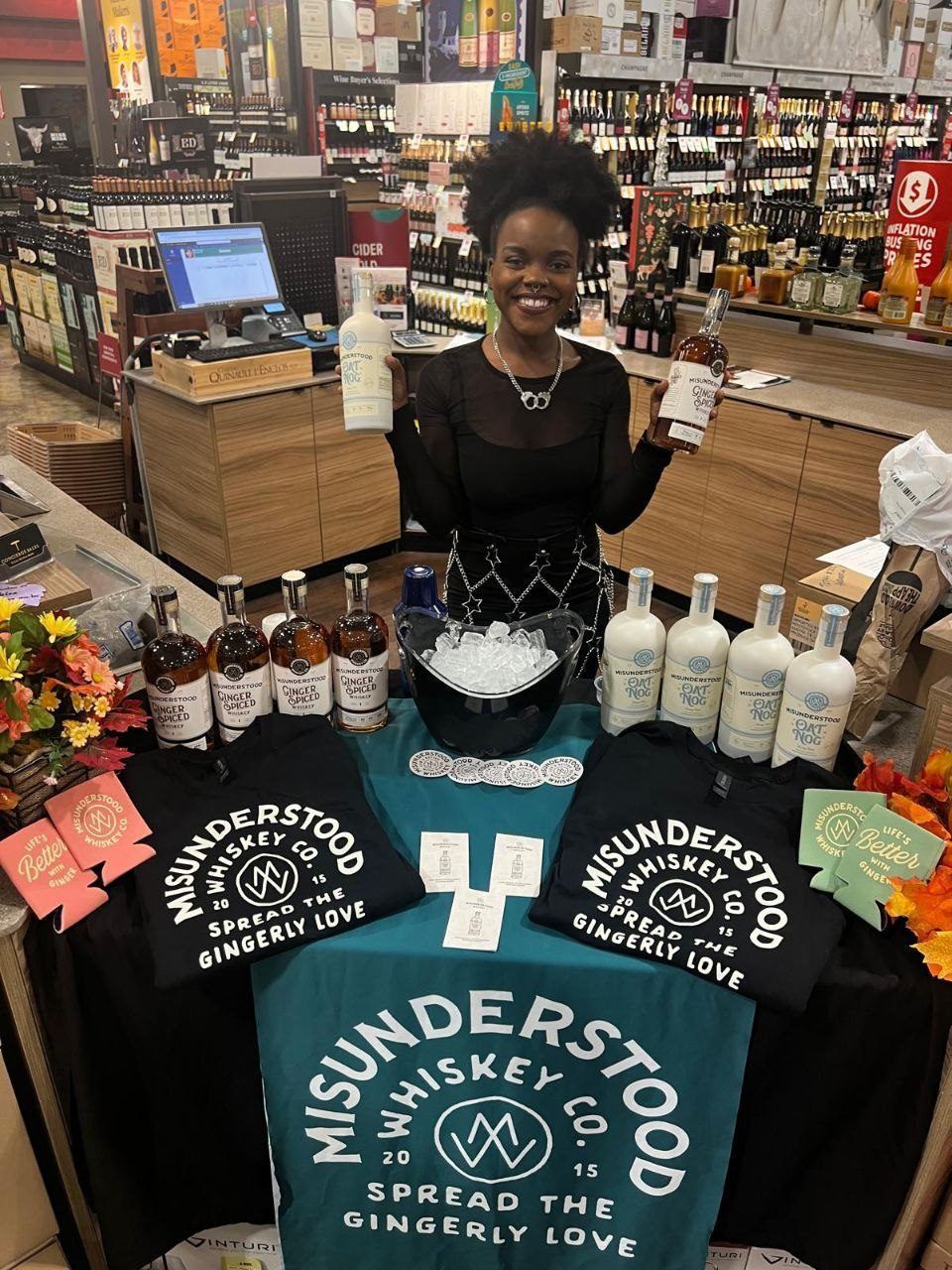 On-Site Activations — Misunderstood Whiskey Co tasting with ambassador holding Ginger Spiced and Oat Nog beside branded tees and koozies