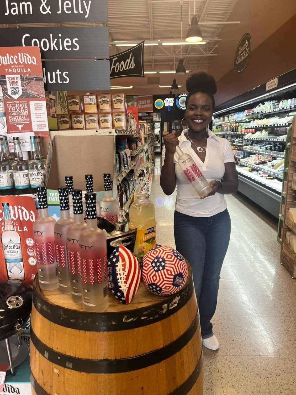 On-Site Activations — Fifty States vodka grocery demo with ambassador, flag-themed footballs on a barrel, and Dulce Vida Tequila signage