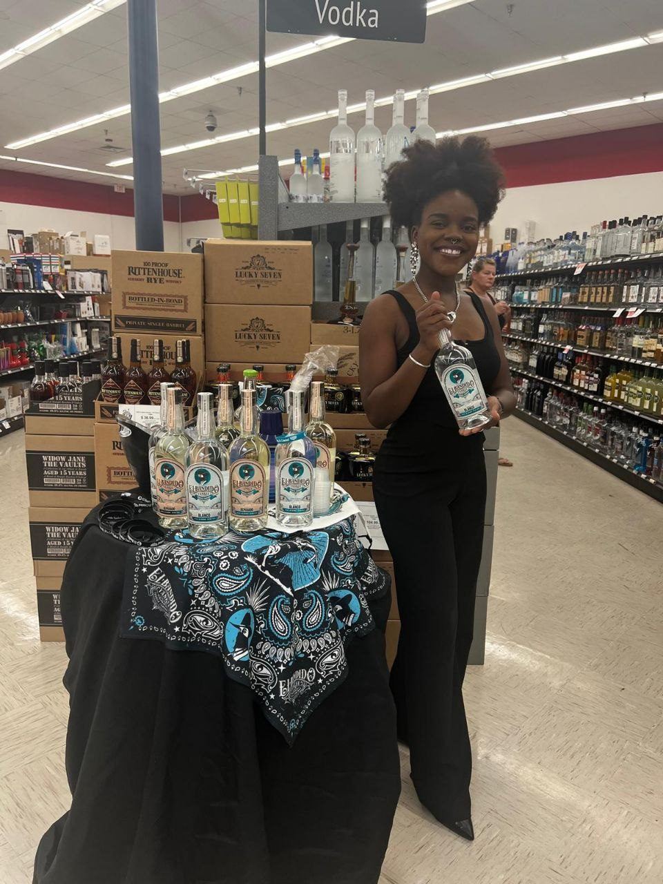 On-Site Activations — El Bandido Yankee tequila tasting with ambassador and bandana-draped table beside Rittenhouse Rye and Widow Jane cases