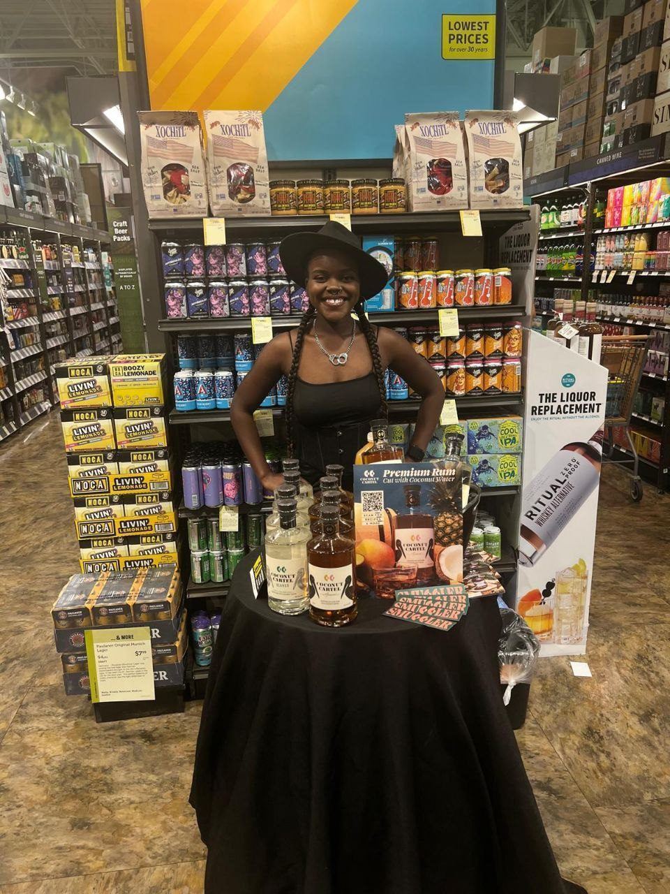 On-Site Activations — Coconut Cartel premium rum tasting with ambassador between NOCA Livin Lemonade stacks and a Ritual Zero Proof banner