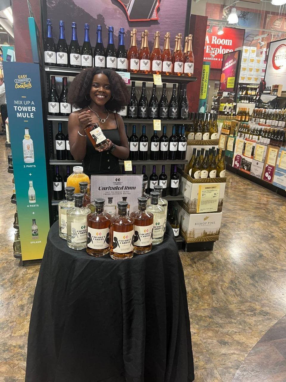 On-Site Activations — Coconut Cartel rum tasting with ambassador, Unrivaled Rum signage, Tower Mule cocktail banner, and Bishop Pine Vineyards cases