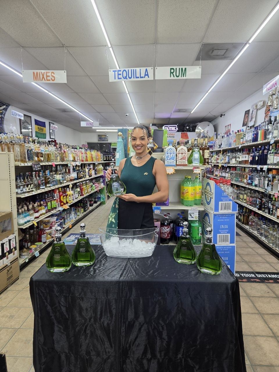 On-Site Activations — Lucky Stash ambassador presenting the green decanter bottle at an in-store tasting table beneath the tequila aisle signs