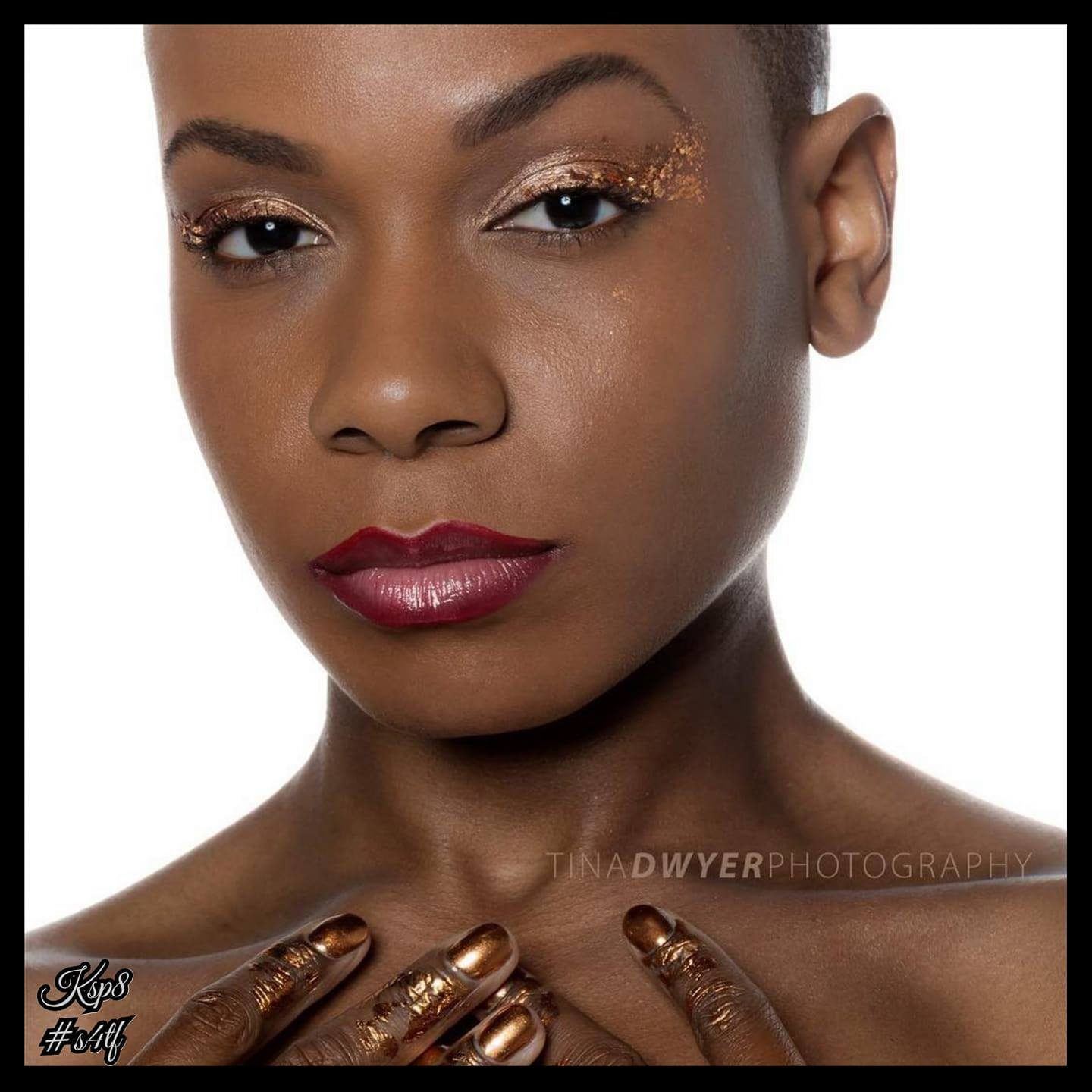 Photography — Studio beauty close-up of a model with copper foil eyeshadow, deep red lips, and copper-painted fingertips