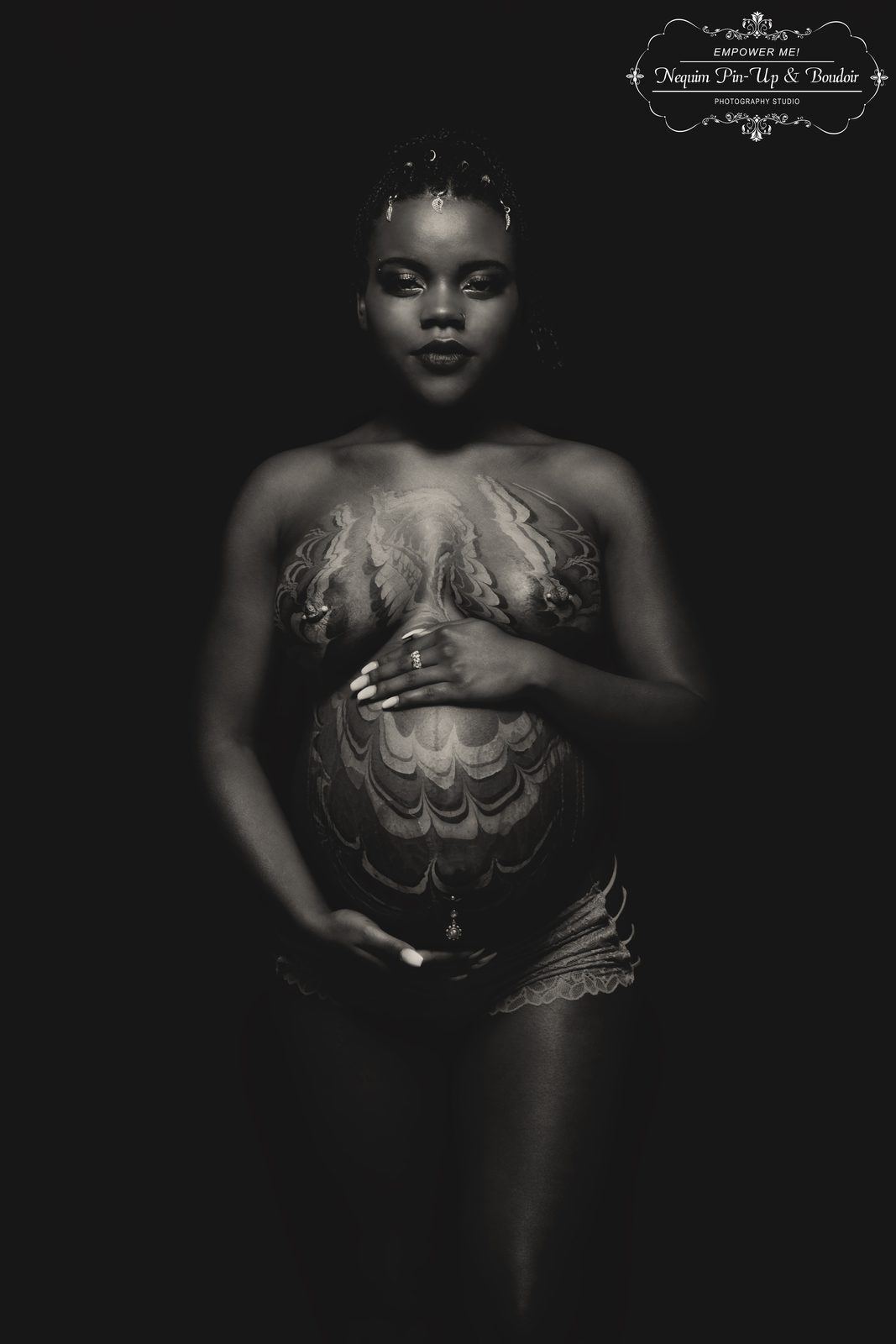 Photography — Black and white maternity portrait of a model with marbled body paint cradling her belly in low-key lighting