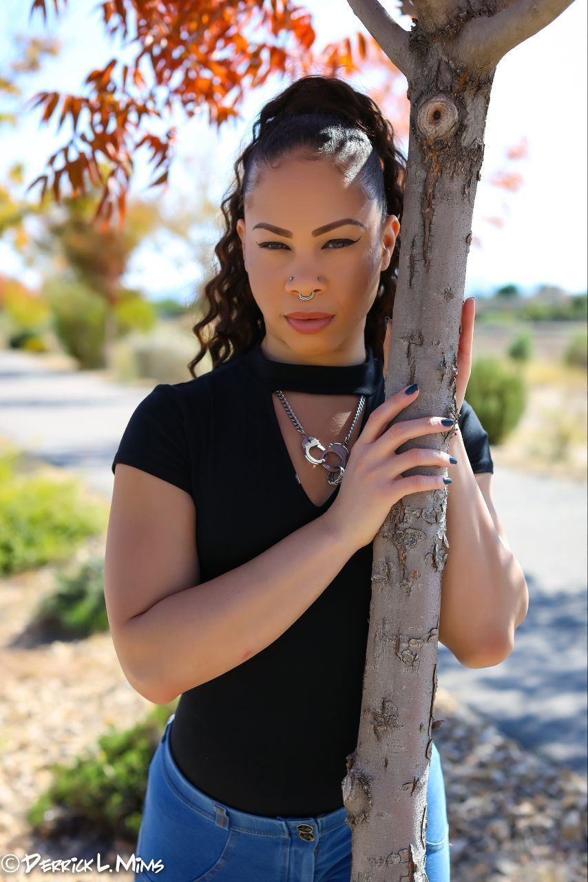 Photography — Model in a black keyhole top and jeans posing beside a slim tree with autumn foliage